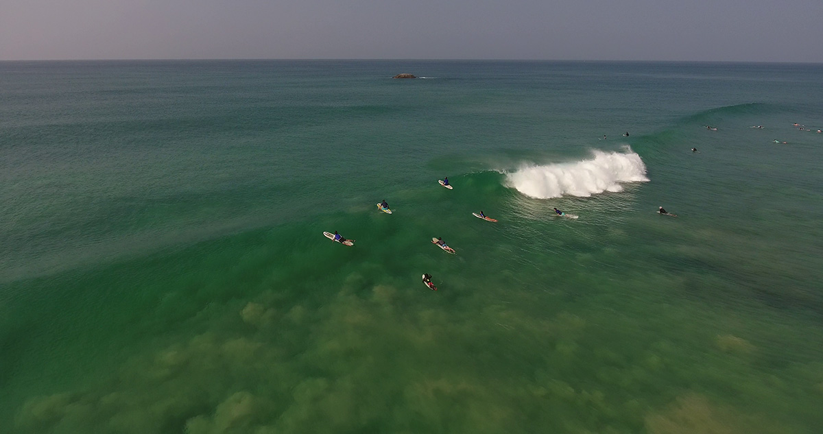 Group of tourists swimming to the middle of the sea to surf
