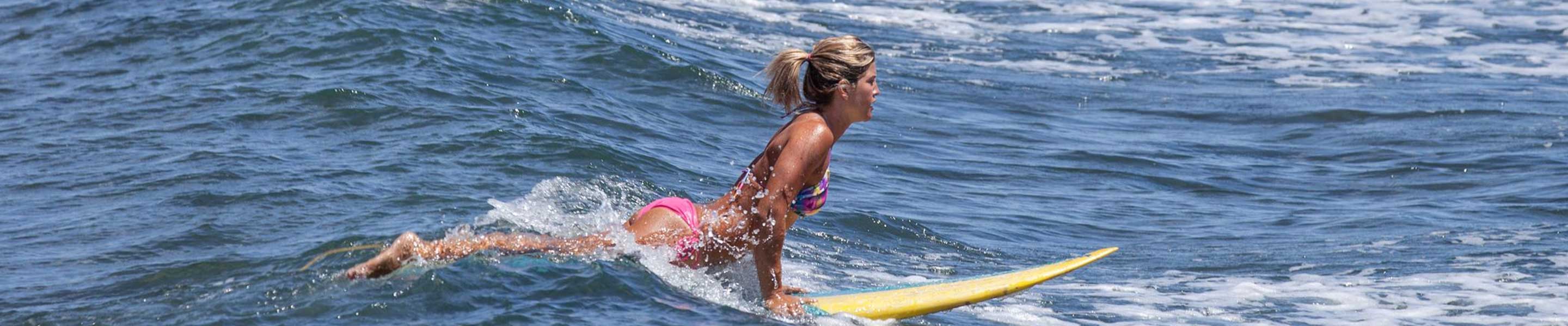 Female beginner attempting to surf in the sea
