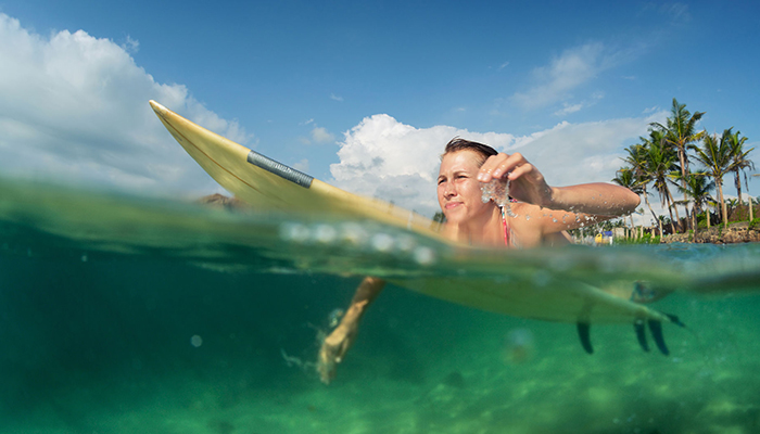 Female surfer paddling towards the waves to surf